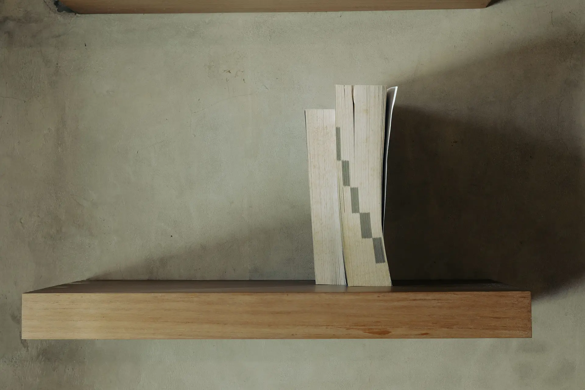 Curated timber library shelving and textured concrete wall styling